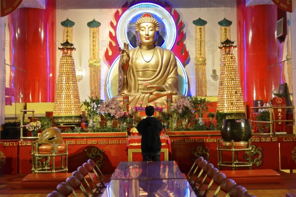 Manhattan, New York City, New York, USA, North America, Person praying in front of a large Buddha statue in a colourful temple, North America
