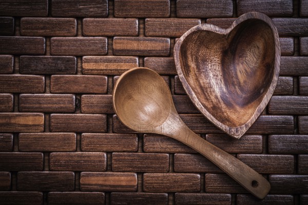 Set of heartshaped wood bowl and spoon on wooden backcloth
