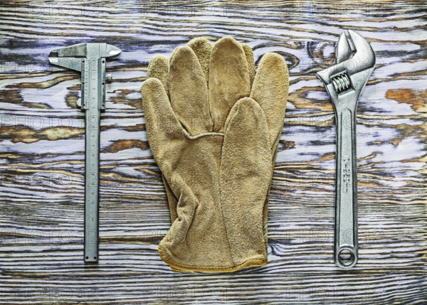 Vernier caliper adjustable spanner safety gloves on wooden board