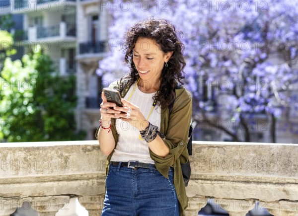 Mid-adult woman using her phone in in a bustling urban environment