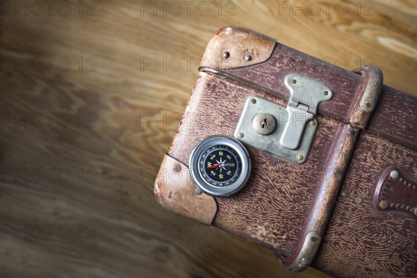 Old vintage suitcase with a compass seen from above, concept for travel, adventure and finding the path, when life changes, rustic wooden background, copy space, selected focus, narrow depth of field