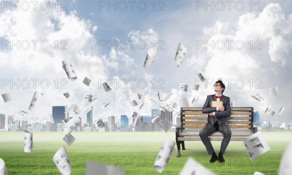 A young student sits on a bench and squeezes the book, looks up