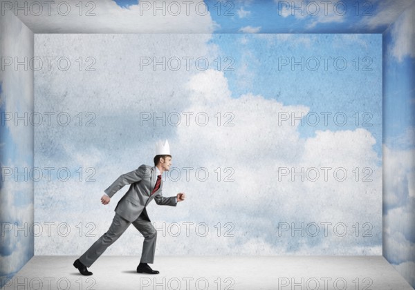 King businessman in elegant suit running in empty room with blue sky on wall