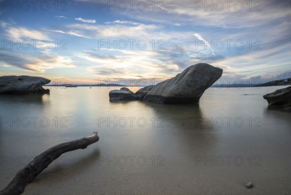 View through rocks on a sandy beach into the sunset. Landscape shot with view to the horizon over the wide sea at the coast of Ouranoupoli, Thessaloniki, Central Macedonia, Greece, Europe