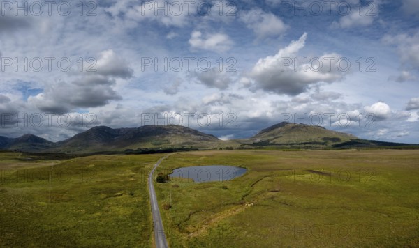 Narrow country road leads into the wild landscape of the Connemara National Park in western Ireland
