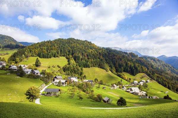 Small village in mountain valley. Picturesque Julian Alps. Beautiful autumn day. Charming pastoral. Green grassy lawns in a mountain valley. Travel to Slovenia