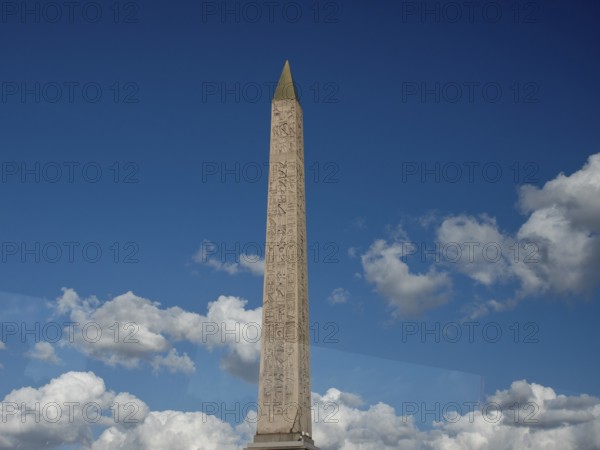 Massive obelisk in front of a clear blue sky with white clouds, Paris, France, Europe