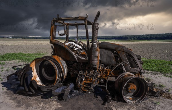 Fully destroyed burnt down tractor on a field