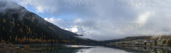 A panorama view of Lake Sufers and Pizzo Tambo and fall foliage forest reflections in the lake