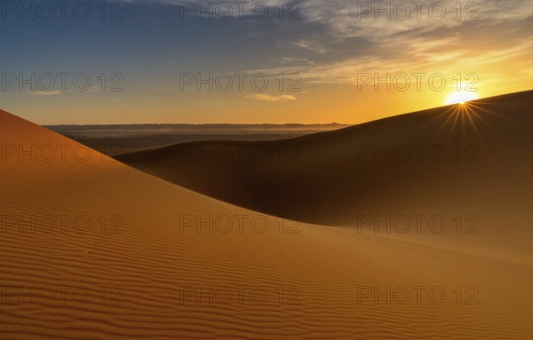 A view of the sand dunes at Erg Chebbi in Morocco at sunset with a sunstar