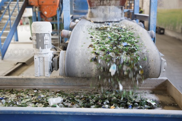 Glass particles for recycling in a machine in a recycling facility. Different glass packaging bottle waste. Glass waste management. Glass recycling is the process of waste glass into usable products