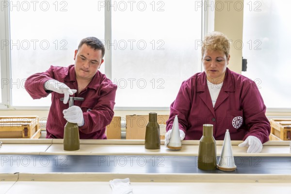Sopot, Bulgaria - May 17, 2016: Workers are tightening explosive elements of anti-tank rocket-propelled grenades (RPG, bazooka) at an assembly line in a munition factory. Working with white gloves