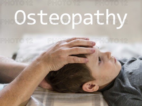 Osteopathy Treatment and word Osteopathy. Elementary age boy's forehead being manipulated by real osteopathic physician