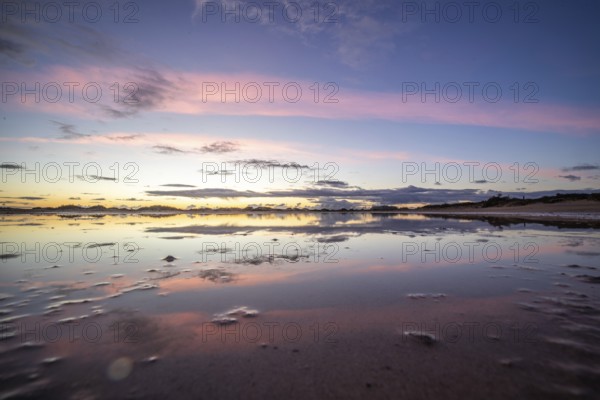 Puddle in a dune by the sea. Reflection of the sunrise in the morning. Bay and coast near Corralejo, Las Palmas province, Spain, Europe
