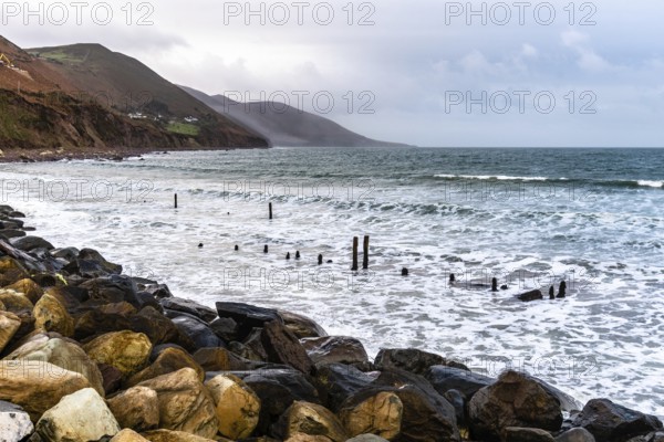 Scenic view of rocky beach in the coast of Ireland against mountains and cloudy sky