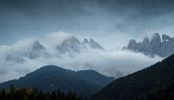 Cloudy fogy sky mountain peaks covered in mist in the morning. Dolomite rocky mountains Italy