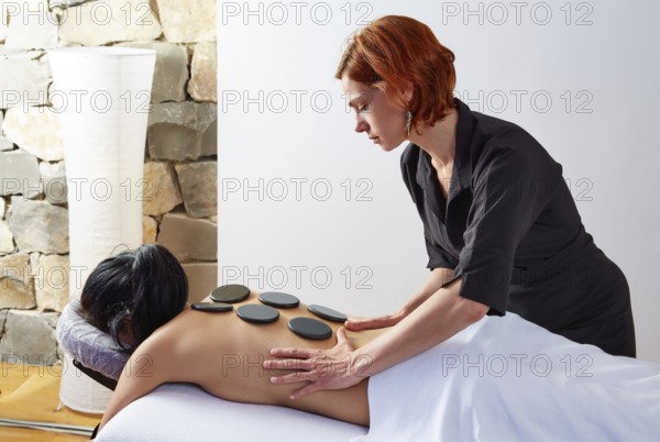 Hot stone massage in woman back with physiotherapist