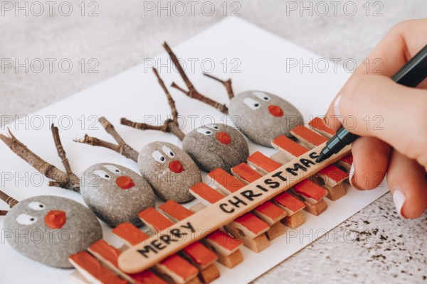 Step by step. Top view. Process kid children craft. Do it yourself Diy Merry Christmas deer on greeting card postcard made of pebbles, sea stones, clothespins and branches on white background. Natural Eco style diy. Gift idea