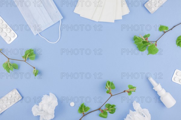Creative flat lay concept of seasonal spring pollen allergy with napkins, pills, face mask, drops in a bottle and fresh green sprouts with buds with copy space background minimal style, template for text