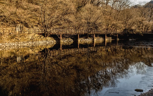Jeongeup-si, South Korea. December 8, 2020: Winter landscape of bridge reflecting in water of shallow river on sunny morning