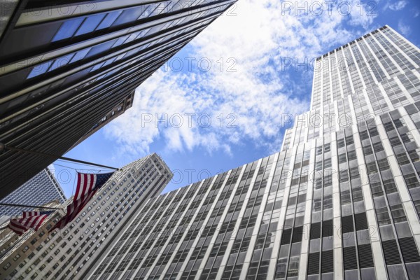Low angle view of American flag and skyscrapers against sky in New York City. Finance, business and technology background