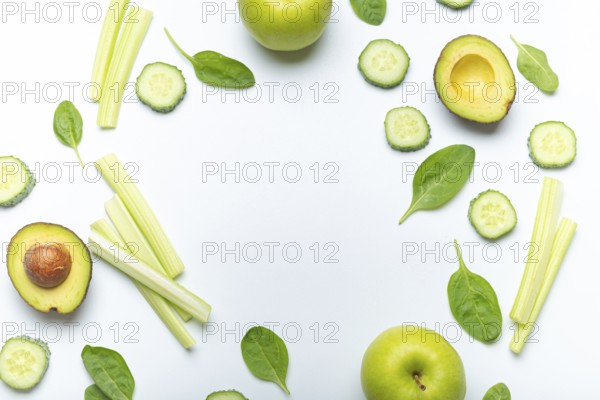 Bottle of green smoothie surrounded by green fruit and vegetables: apples, avocado, spinach, celery sticks, cucumber on white simple background top view. Diet, healthy nutrition, detox concept, food photography, food photography