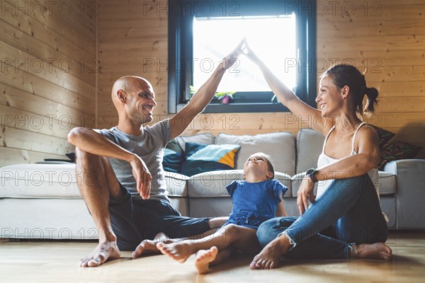 Young family with a girl, spending time at home on the weekends. Loving family resting on the couch, playing, watching television