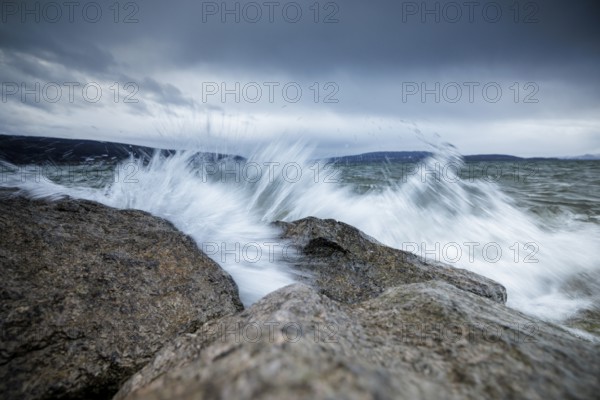 Waves crashing against rocks with dramatic sky in the background, harbour, Mittelzell, Reichenau, Lake Constance, Baden-Württemberg, Germany, Europe