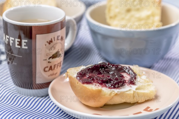 Mini butter brioche with jam and coffee mug on a light blue background