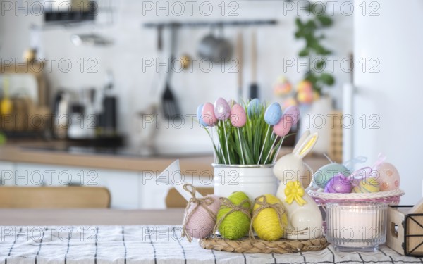 Easter decoration of colorful eggs in a basket and a rabbit on the kitchen table in a rustic style. Festive interior of a country house