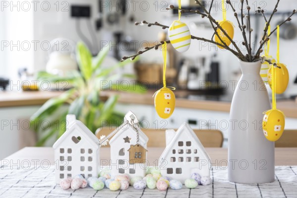 Key to house of cozy home with Easter decor with rabbit and eggs on table of kitchen. Building, design, project, moving to new house, mortgage, insurance, rent and purchase real estate