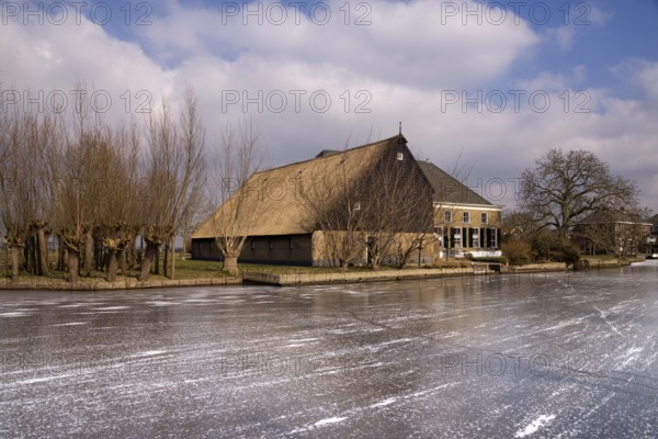 Frozen river the Graafstroom with on the other side a monumental farm in the South Holland village of Bleskensgraaf