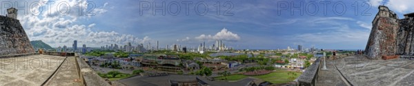 Panoramic view of a cityscape from a historical fort with a mix of urban buildings and greenery under a blue sky, Cartagena de Indias, Bolívar, Colombia, South America