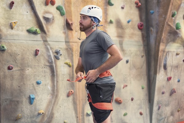 Man climber preparing to climb artificial indoor climbing wall