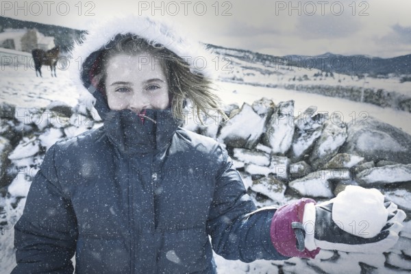 Blond kid girl playing with snow ball in winter