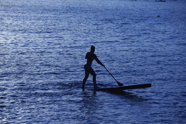 SUP Stand up Surf girl with paddle at sunset