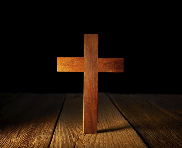 Christian wood cross on black and wooden background