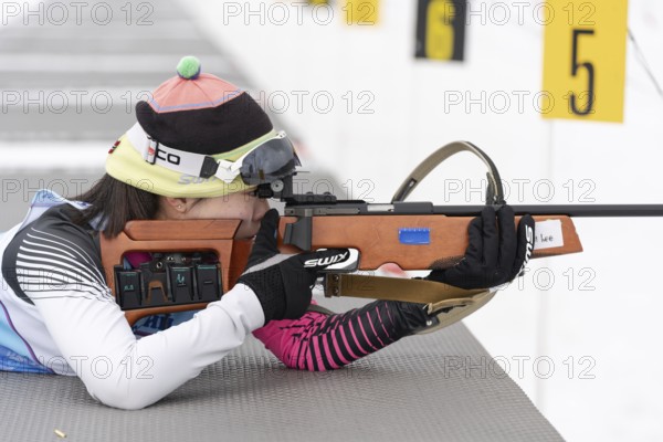 Sportswoman biathlete Yu Seolhee South Korea rifle shooting in prone position. Biathlete in shooting range of Open regional youth biathlon competitions East Cup. Kamchatka, Russia, April 12, 2019, Europe