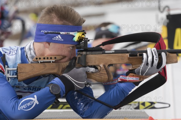 Sportsman biathlete rifle shooting, aiming, reloading rifle in prone position. Junior biathlon competitions East Cup. Biathlete Aleksander Kozulin in shooting range. Kamchatka, Russia, April 12, 2019, Europe