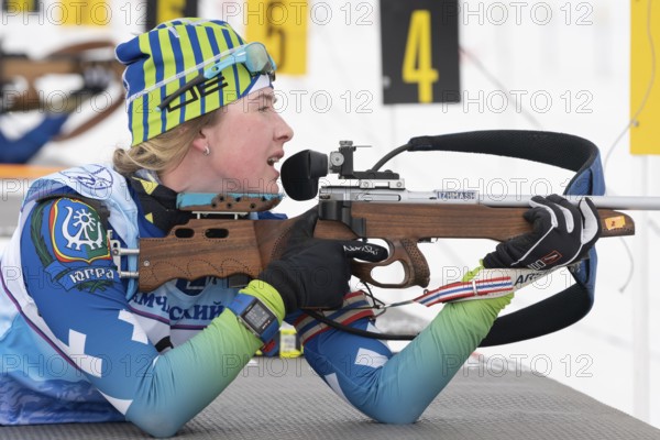 Sportswoman biathlete Legostaeva Anastasia rifle shooting in prone position. Biathlete in shooting range of Open regional junior biathlon competitions East Cup. Kamchatka, Russia, April 12, 2019, Europe