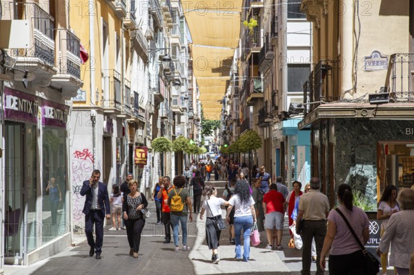 Granada, Spain, May 27, 2019: People walking in a charming narrow shopping street in the historic city centre, Europe