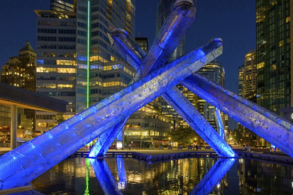 Modern Olympic fire installation at night with blue lighting and surrounding skyscrapers in the city, Vancouver, British Columbia, Canada, North America