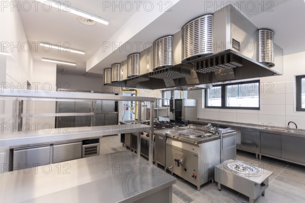 A contemporary commercial kitchen featuring stainless steel appliances and bright, efficient lighting