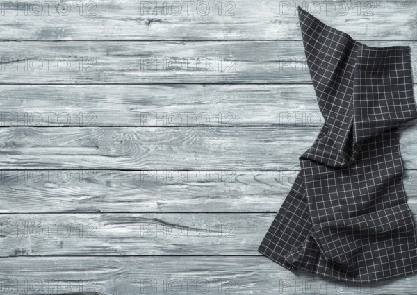 Gray wooden table with balck and white dark linen kitchen towel or textile napkin flat lay. Dark tablecloth on old gray wood tabletop. Copy space for text. Can use as mock up for design