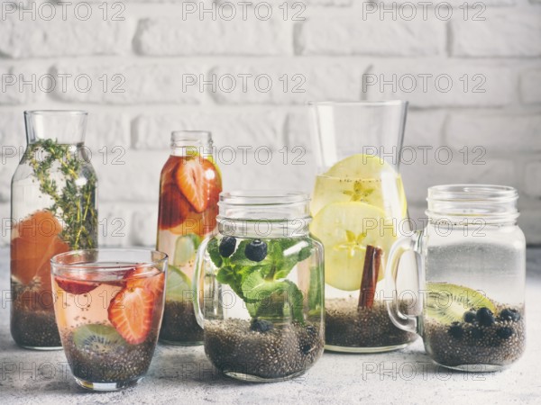 Different chia water in glass on gray background. Chia infused detox water with berries, fruits and herbs. Healthy eating, drinks, diet, detox concept. Copy space for text
