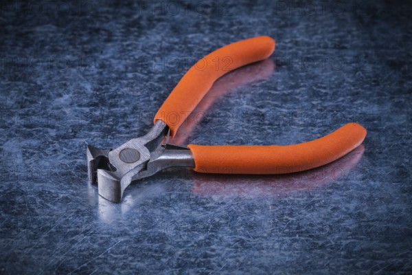 Insulated electric metal nippers on metallic background electricity concept