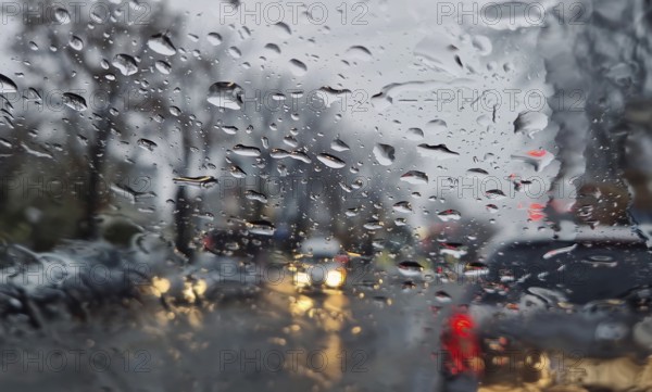 Melted snow and rain drops on the windshield of a car. Blurred outdoor view, winter season sleet as seen out of vehicle window