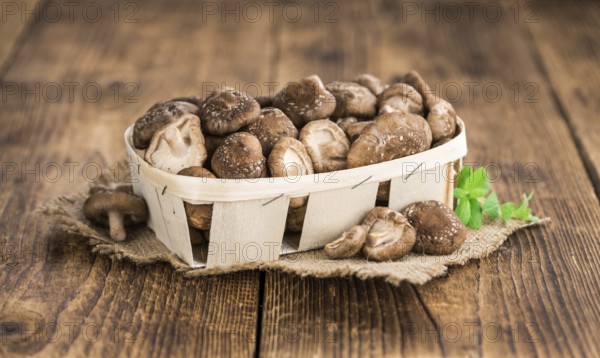 Raw Shiitake mushrooms as high detailed close-up shot on a vintage wooden table, selective focus