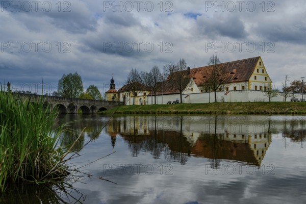 Old building and bridge reflected in a river under a cloudy sky, Tirschenreuth, Upper Palatinate, Bavaria, Germany, Europe