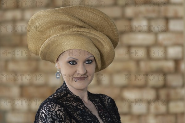 Woman in black lace dress with golden turban in front of beige wall, staged portrait shooting, studio shot, Mindelheim, Bavaria, Germany, Europe